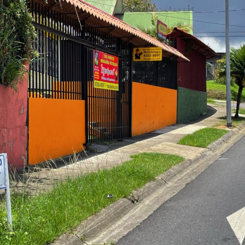 Casa color amarillo con muros anaranjados, a mano izquierda.